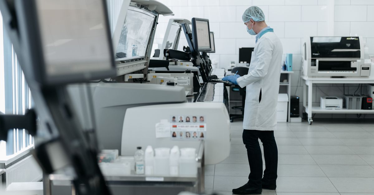 A scientist in a lab coat using advanced laboratory equipment in a clean, modern lab.