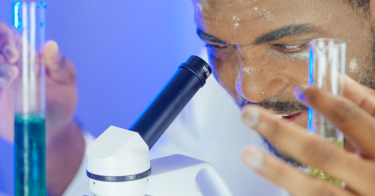 Biochemist using microscope and test tubes for laboratory experiment.