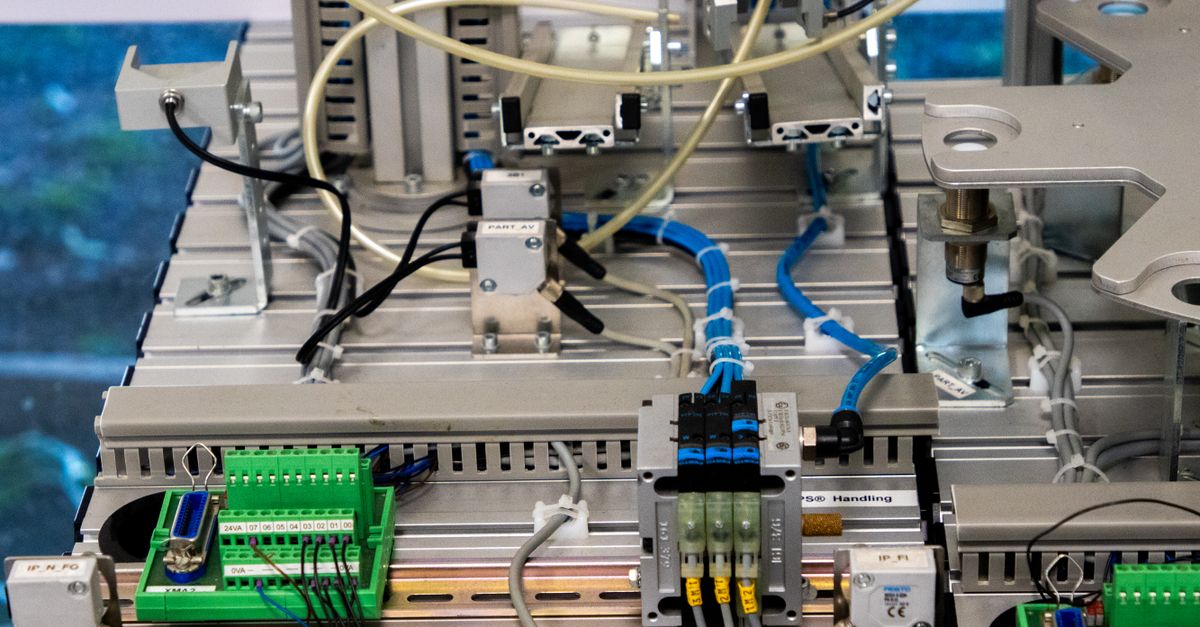 Close-up of industrial equipment showcasing electronic wiring and sensors in a manufacturing setup.