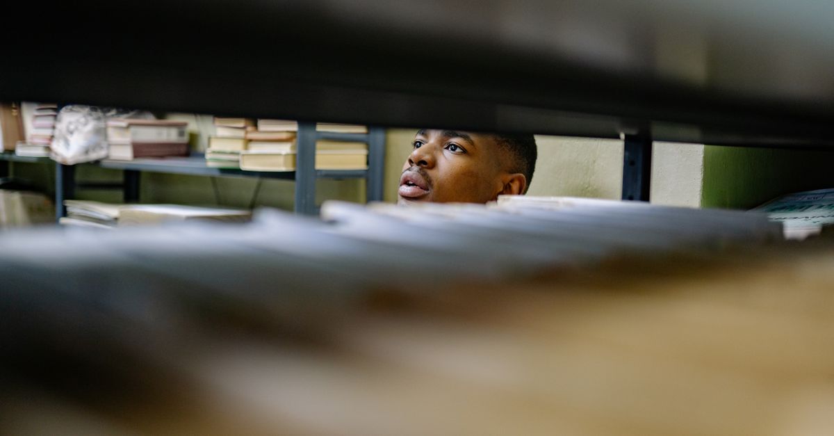 A man browsing through files in a library or archive, focused on tasks.
