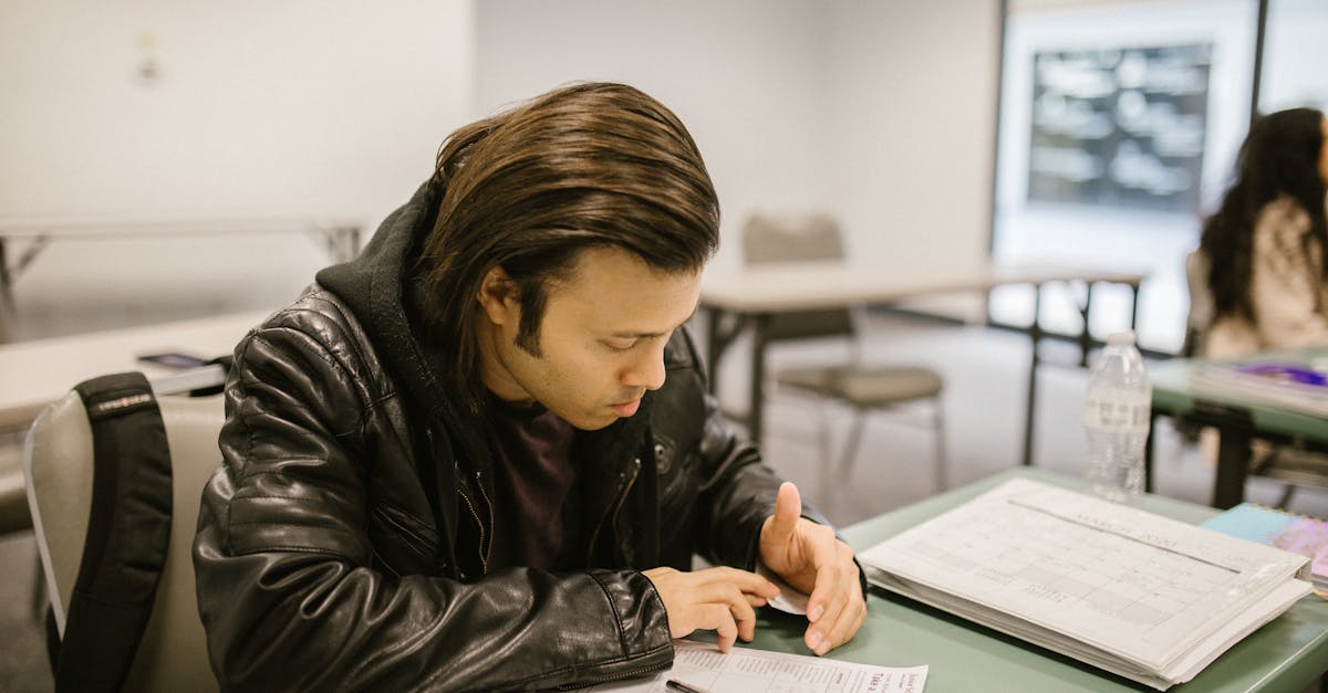 A man concentrating on an exam paper in a classroom setting, emphasizing education.