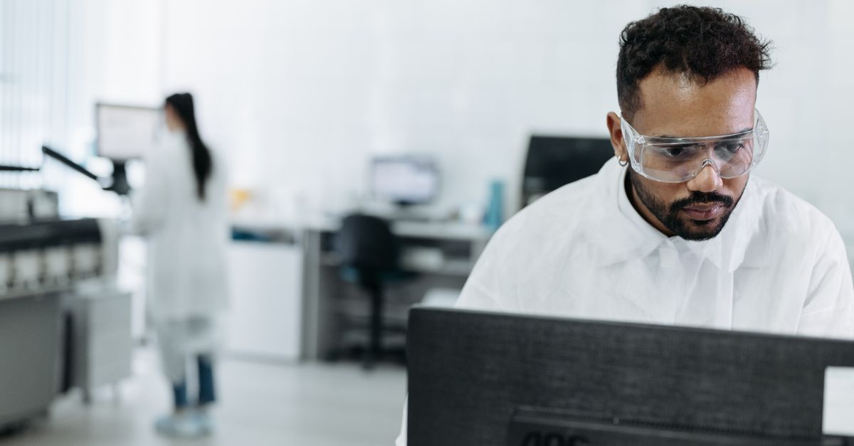 A scientist working diligently at a computer in a modern laboratory.