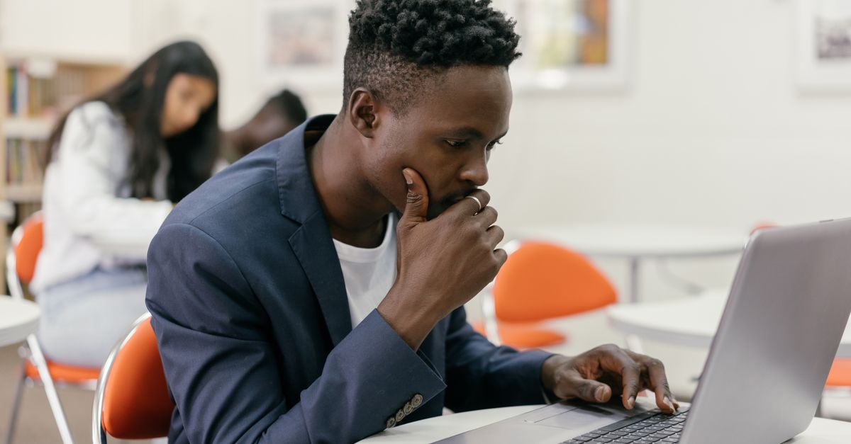 Focused student sitting at a laptop in a modern classroom setting.